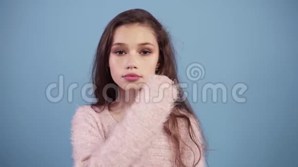 白人少女在蓝色背景下保守秘密或要求保持沉默抿着嘴严肃的脸视频的预览图