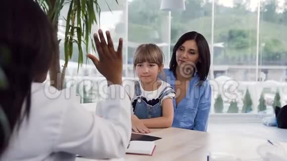 小女孩坐在她母亲的膝盖上给女医生五个视频的预览图