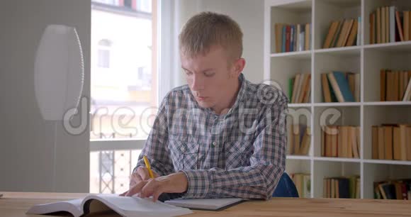 白种人学生写作业在图书馆集中和专注的肖像视频的预览图