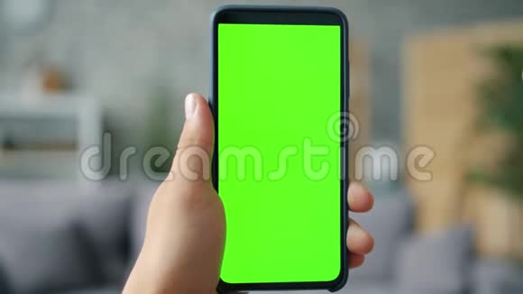 公寓中男性手握色度键绿色屏幕智能手机的特写视频的预览图