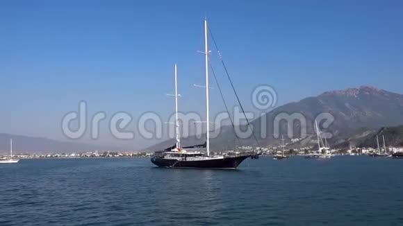 美丽的大游艇停泊在蓝色平静的大海上背景是美丽的小山和船在一个视频的预览图