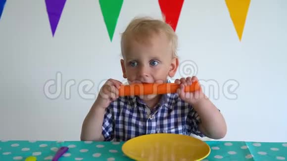 可爱的蹒跚学步的男孩双手拿着胡萝卜咬它万向节运动视频的预览图