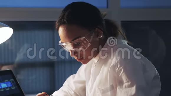 关闭在电子实验室工作的戴防护眼镜的非裔美国工程师视频的预览图