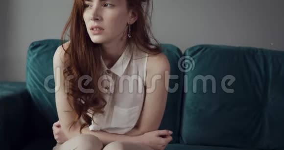 红发女人坐在沙发上感到肚子痛和愤怒视频的预览图