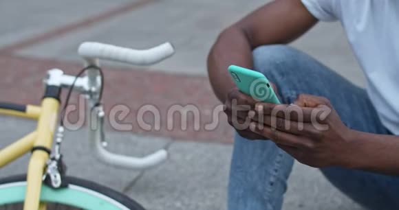 在城市的台阶上骑自行车的时候用智能手机近距离拍摄非裔美国人的双手视频的预览图
