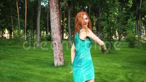 红头发的年轻女子穿着湿衣服霍莉在公园里笑着跳着视频的预览图