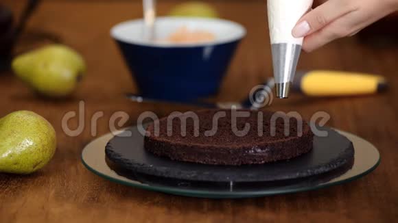 糖果女人用梨馅做巧克力蛋糕面包师女人把奶油挤在蛋糕上视频的预览图