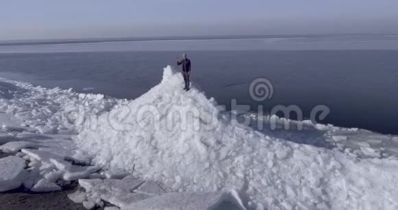 鸟瞰年轻活跃的快乐男子停留在冰冰冰川附近的冬季海织手视频的预览图