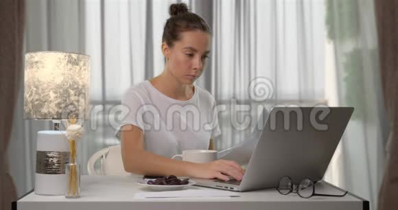 女人在公寓里做自由职业者她坐在桌子旁用电脑打字视频的预览图
