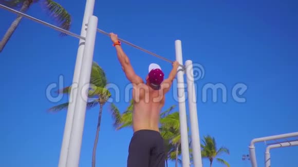 年轻的肌肉男在户外水平杆上做运动视频的预览图