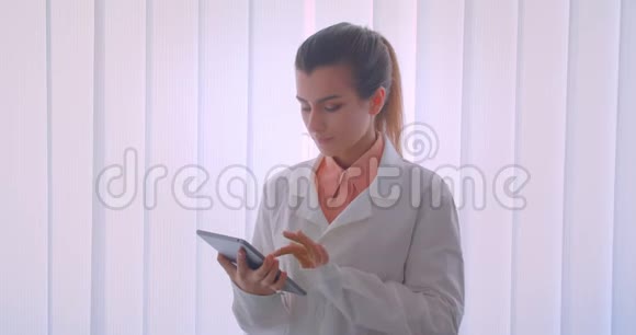 年轻迷人的白种人女医生手持平板电脑的特写肖像并显示绿色的色度键屏幕视频的预览图