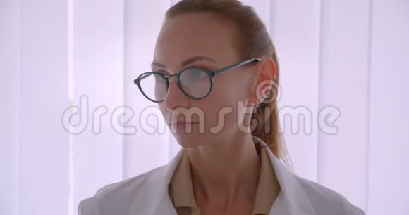 成功的白种人女医生穿着白大褂戴着眼镜在贾洛西的背景下对着镜头微笑视频的预览图