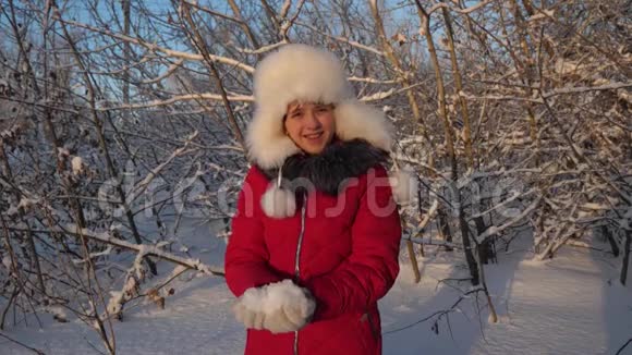 美丽的少女在冬季公园玩耍幸福的女孩在森林日落时用手举起雪白雪皑皑视频的预览图