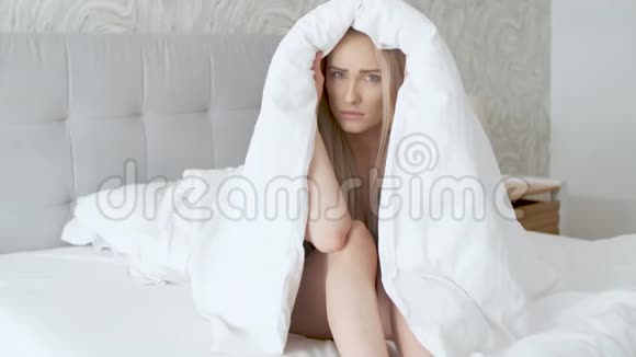 忧郁的年轻白种人模特摆在温暖的毯子包裹的舒适床上视频的预览图