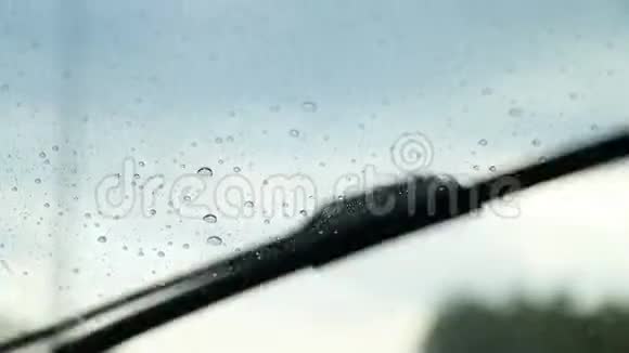 雨滴落在挡风玻璃上顺着行驶车辆的玻璃流下来雨刷被清洗干净视频的预览图