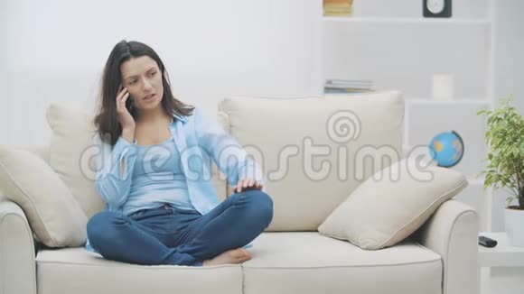 穿着蓝色衬衫的漂亮女人一边打电话一边坐在家里慢动作复制空间4K视频的预览图