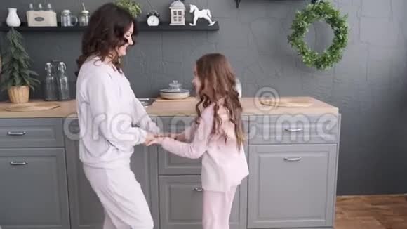 厨房里的幸福家庭妈妈和女儿穿着睡衣玩和跳舞妈妈正在厨房和女儿跳舞视频的预览图