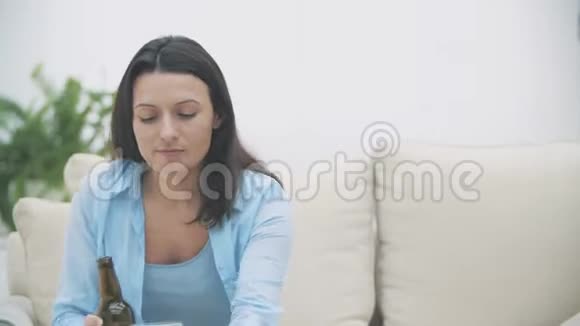 微笑开朗的女人正在喝啤酒坐在家里的沙发上复制空间快关门4K视频的预览图