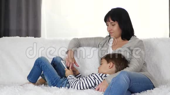 幸福家庭母子花时间玩平板电脑女人和孩子坐在沙发上的概念视频的预览图