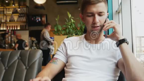 忙碌的年轻人在咖啡馆里用手机说话视频的预览图