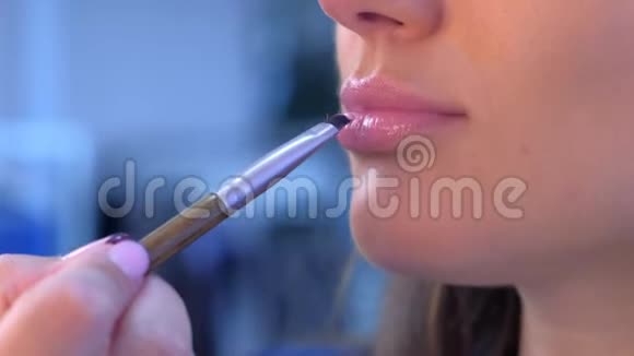 化妆师将唇彩用刷子涂在女孩模特的嘴唇上化妆视频的预览图