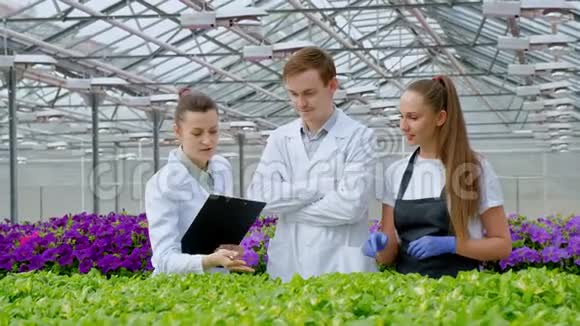 一个年轻人和两个女人穿着白色外套和黑色围裙三位科学家生物学家或农学家研究视频的预览图