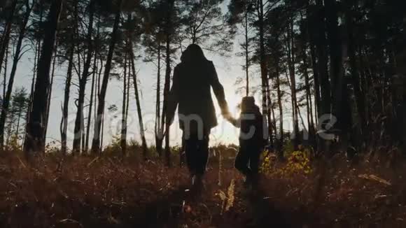 一名妇女和一名儿童穿过森林的剪影视频的预览图