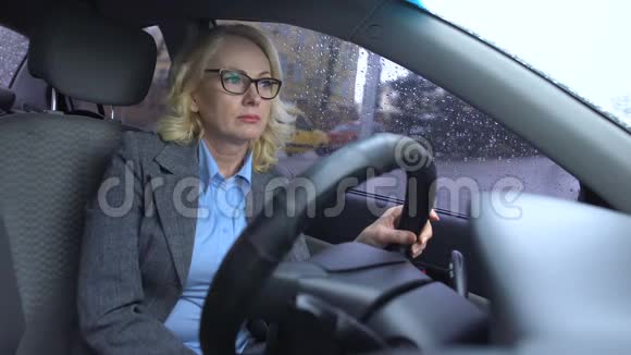 精疲力竭的老年妇女西装革履地坐在车里车窗上的雨滴抑郁视频的预览图