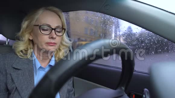 成熟的商业女性患血压障碍坐汽车雨天视频的预览图