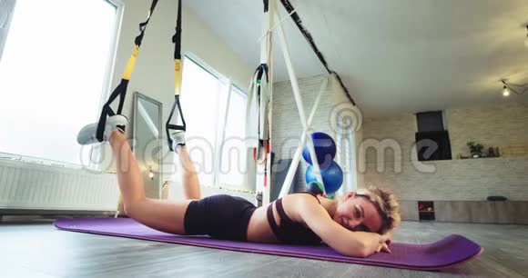 在一个宽敞的有氧运动工作室里一位运动的金发女人在运动垫上躺了一段轻松的时光视频的预览图