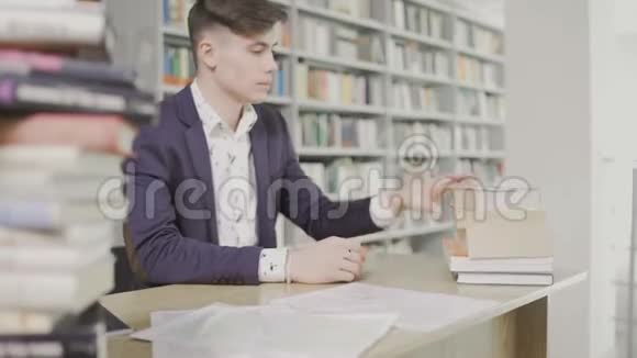 穿西装的年轻学生读一本大的英语教科书视频的预览图