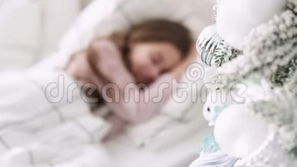 小女孩睡在圣诞树的背景上圣诞节睡觉的女孩视频的预览图