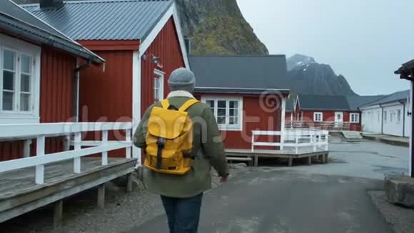 男性游客步行穿过村庄雷恩洛福顿挪威蓝天有典型的罗布房屋男人视频的预览图