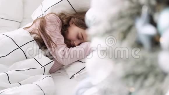 小女孩睡在圣诞树的背景上圣诞节睡觉的女孩视频的预览图