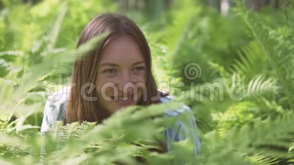 一个女人坐在蕨类植物丛中微笑视频的预览图