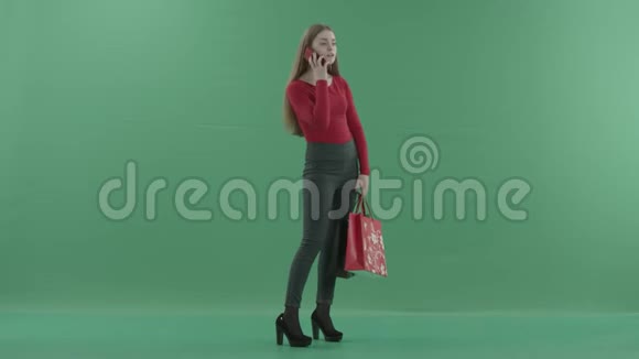 穿着休闲服的漂亮女人拿着购物袋在手机上说话她站在右边视频的预览图