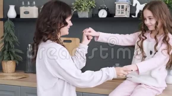 厨房里的幸福家庭妈妈和女儿穿着睡衣玩和跳舞妈妈在厨房拥抱女儿视频的预览图
