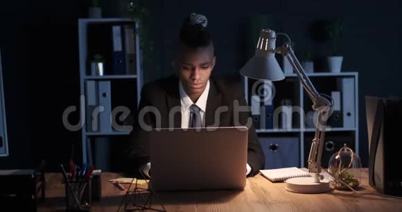 疲倦的商人用笔记本电脑和手机在夜间办公视频的预览图