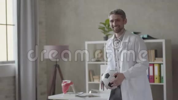 英俊的积极成功和满意的人穿着白色长袍在现代诊所办公室玩球快乐视频的预览图