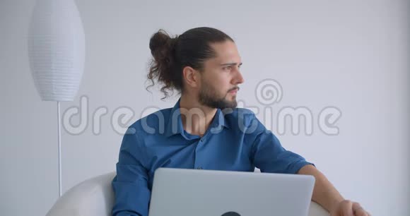 扎着马尾辫的现代自由职业者手提电脑坐在轻便的办公室里忙碌而集中视频的预览图