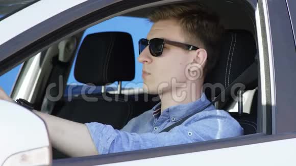 穿着休闲装和太阳镜的布鲁内特男子正在驾驶绿色屏幕背景的汽车他坐在白色的车里视频的预览图
