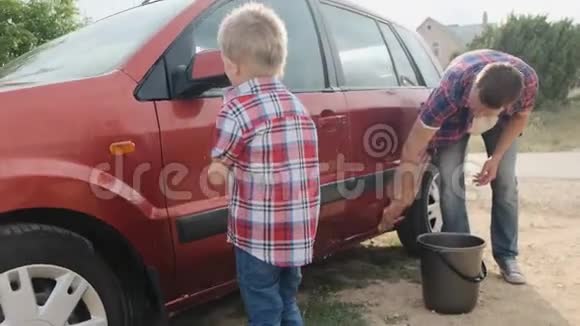 年轻的父亲和他的小儿子一起洗慢车视频的预览图