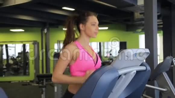 漂亮的年轻女孩在健身房的跑步机上跑步视频的预览图