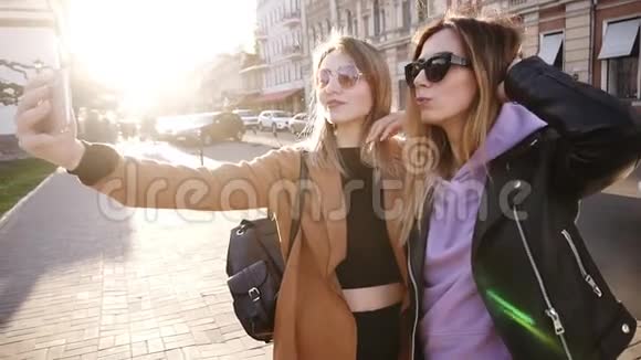 两位年轻的白人时尚女性戴着墨镜自拍和tonque一起大笑街头生活写真视频的预览图