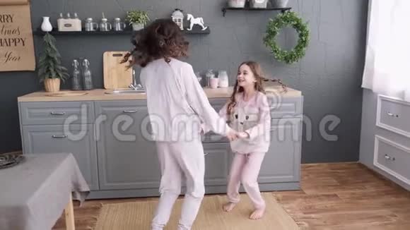 厨房里的幸福家庭妈妈和女儿穿着睡衣玩和跳舞妈妈正在厨房和女儿跳舞视频的预览图