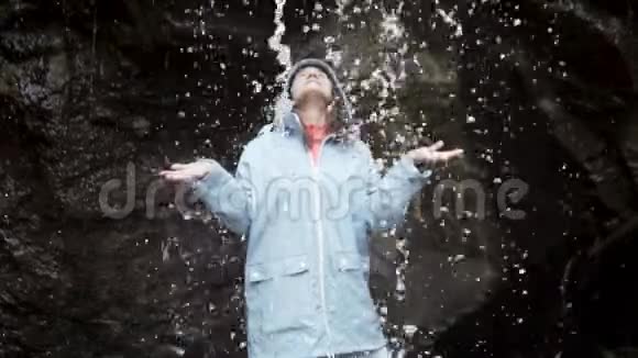 一条瀑布在浇灌一个年轻女子视频的预览图