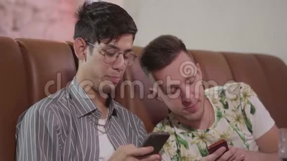 两个男朋友在餐厅休息的肖像坐在皮革沙发上谈笑风生两个男人视频的预览图