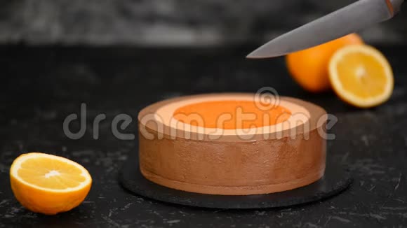 女人用菜刀切橙巧克力慕斯蛋糕视频的预览图