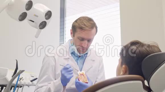 性格开朗成熟的男牙科医生一边对着镜头微笑一边教育小病人视频的预览图