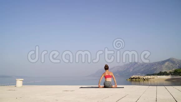 在海边坐在瑜伽体式中的女性的后景背景是山脉视频的预览图